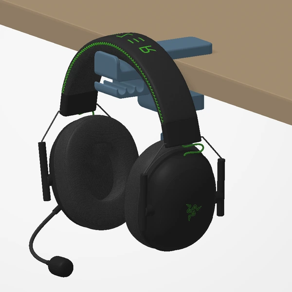 Headphones hanging from the Desk Clamp Headphone Holder under a desk edge